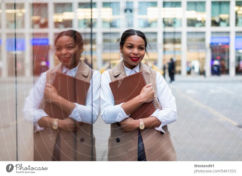 Portrait of smiling businesswoman leaning against glass pane businesswomen business woman business women portrait portraits smile glass panes business people