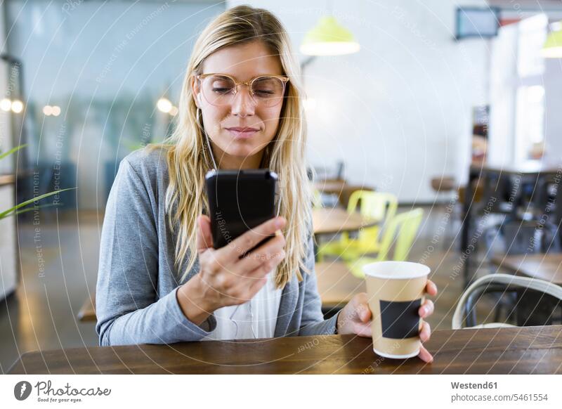 Young woman texting with her mobile phone while drinking coffee in the coffee shop business life business world business person businesspeople business woman