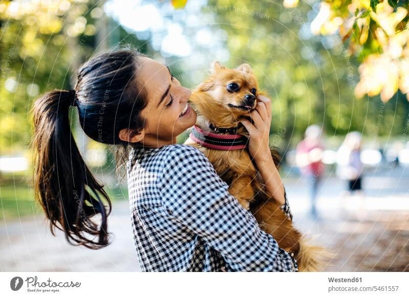 Happy young woman holding dog in a park animals creature creatures domestic animal pet Canine dogs relax relaxing smile embrace Embracement hug hugging delight