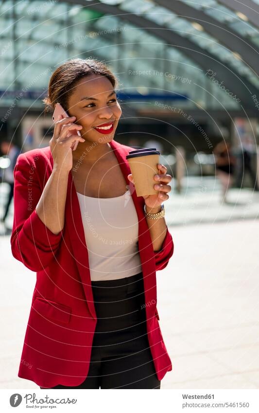 Portrait of smiling businesswoman with coffee to go on the phone, London, UK human human being human beings humans person persons African black black ethnicity