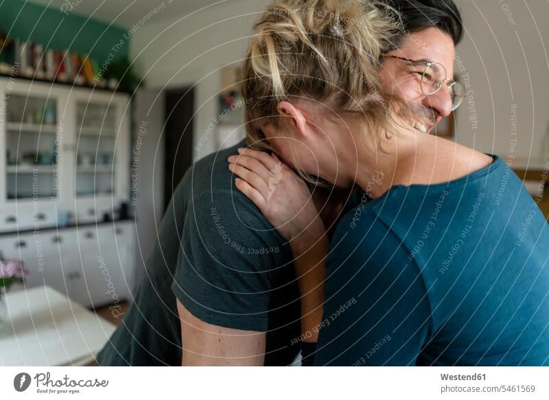 Happy couple embracing in kitchen at home Eye Glasses Eyeglasses specs spectacles smile embrace Embracement hug hugging delight enjoyment Pleasant pleasure