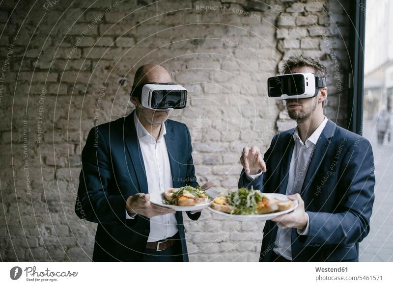 Senior and mid-adult businessman wearing VR glasses holding plate with a meal generation business life business world business person businesspeople associate