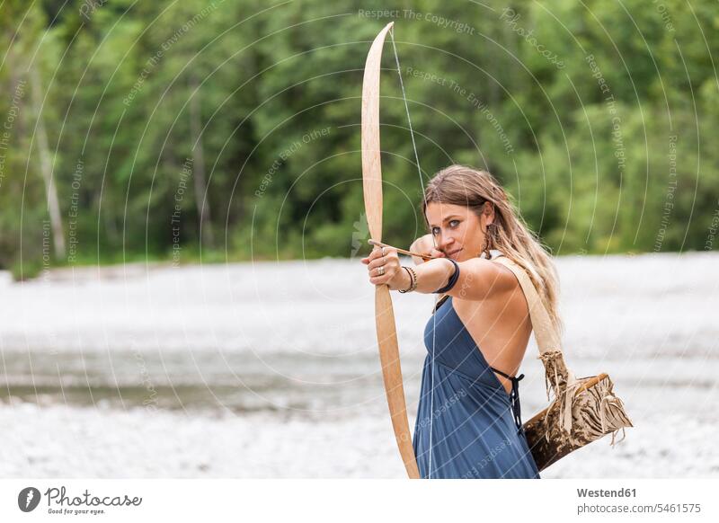 Archeress aiming with a bow in the nature natural world woman females women archers female archer archeress Archery Bows bows Adults grown-ups grownups adult