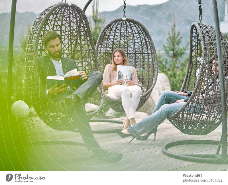Colleagues having a break sitting in hanging chairs Seated smiling smile colleagues Break Swinging Chair Swinging Chairs enjoying indulgence enjoyment savoring