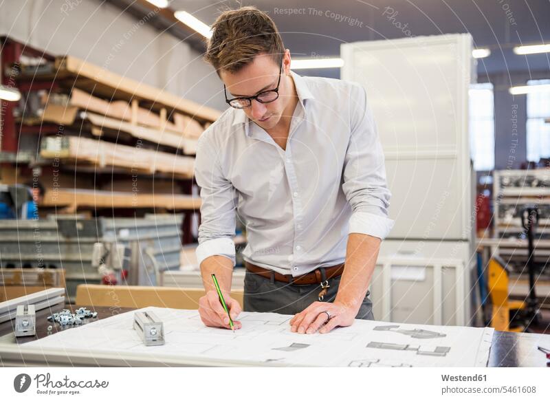 Young businessman in factory working on plan factories plans At Work Businessman Business man Businessmen Business men business people businesspeople