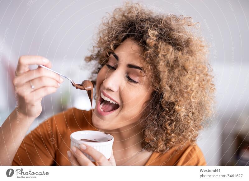 Portrait of happy woman eating chocolate spread at home human human being human beings humans person persons curl curled curls curly hair Bowls hold delight