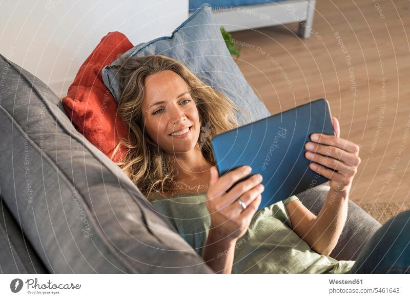 Happy woman realxing on couch at home using tablet relaxed relaxation digitizer Tablet Computer Tablet PC Tablet Computers iPad Digital Tablet digital tablets