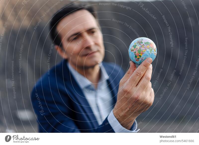 Mature businessman holding a globe on a disused mine tip human human being human beings humans person persons caucasian appearance caucasian ethnicity european
