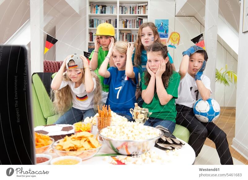 Group of kids watching soccer world championship with table full of sweets and snacks flag flags home at home suspense watching TV Looking At Tv