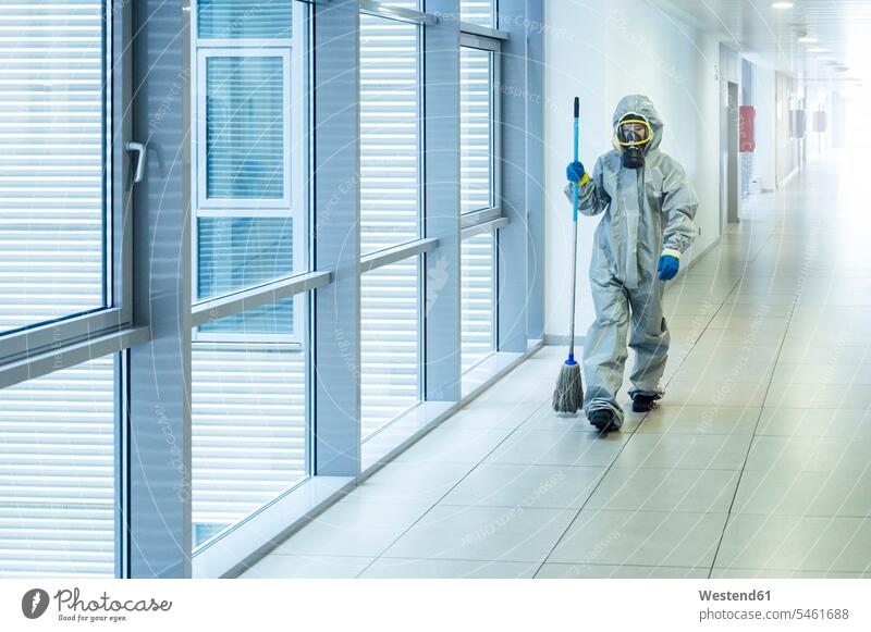 Cleaning staff walking with cleaning mop in corridor, wearing protective clothing human human being human beings humans person persons caucasian appearance