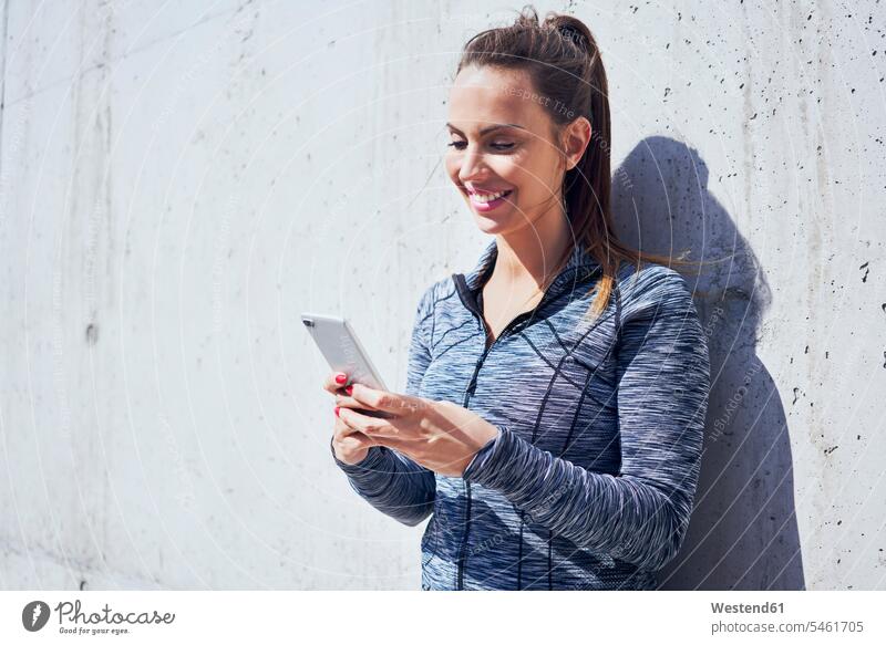 Portrait of happy woman using her smartphone mobile phone mobiles mobile phones Cellphone cell phone cell phones females women jogger joggers female jogger