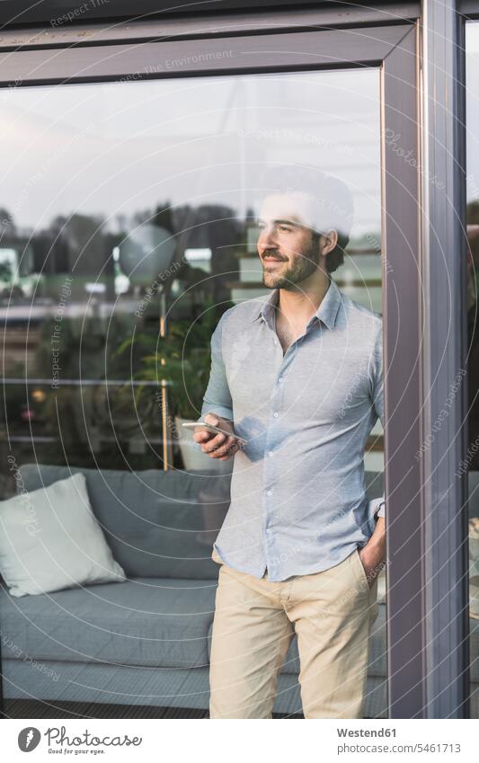 Young man looking out of window, using smartphone copy space confidence confident standing wireless Wireless Connection Wireless Technology