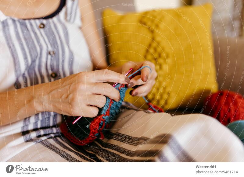 Mature woman knitting while sitting on sofa at home color image colour image indoors indoor shot indoor shots interior interior view Interiors casual clothing