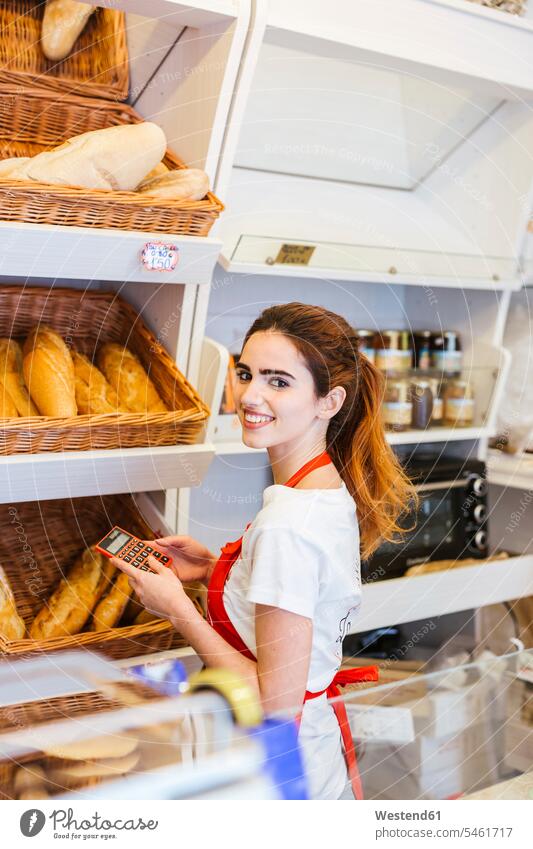 Young woman working in a bakery and using calculator human human being human beings humans person persons caucasian appearance caucasian ethnicity european 1