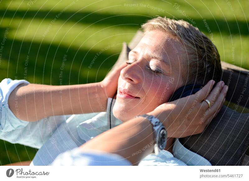 Portrait of woman listening music with headphones in the garden gardens domestic garden portrait portraits females women hearing headset Adults grown-ups