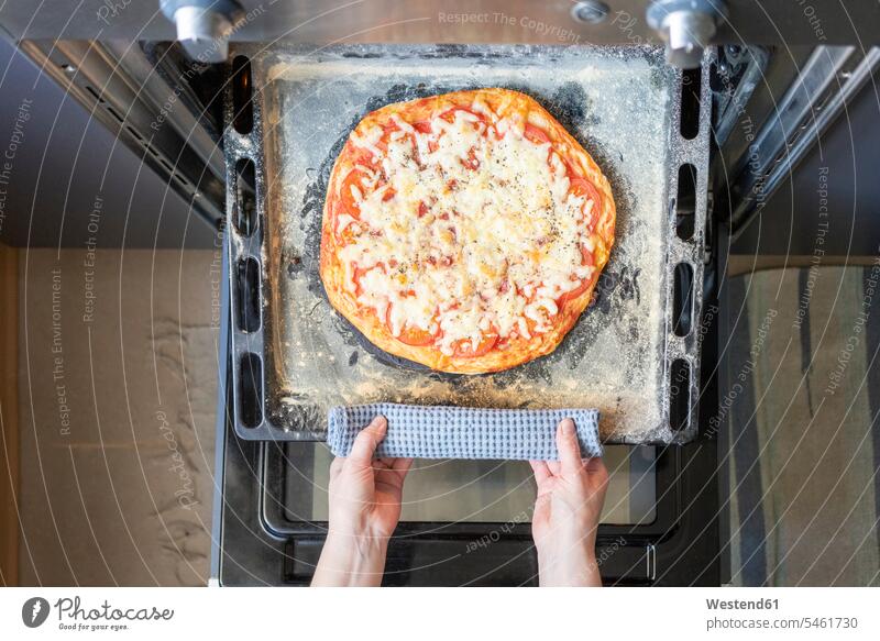 Woman's hands taking tray with baked pizza out of oven pull at home heat Hot Temperature free time leisure time Lifestyle Alimentation food Food and Drinks