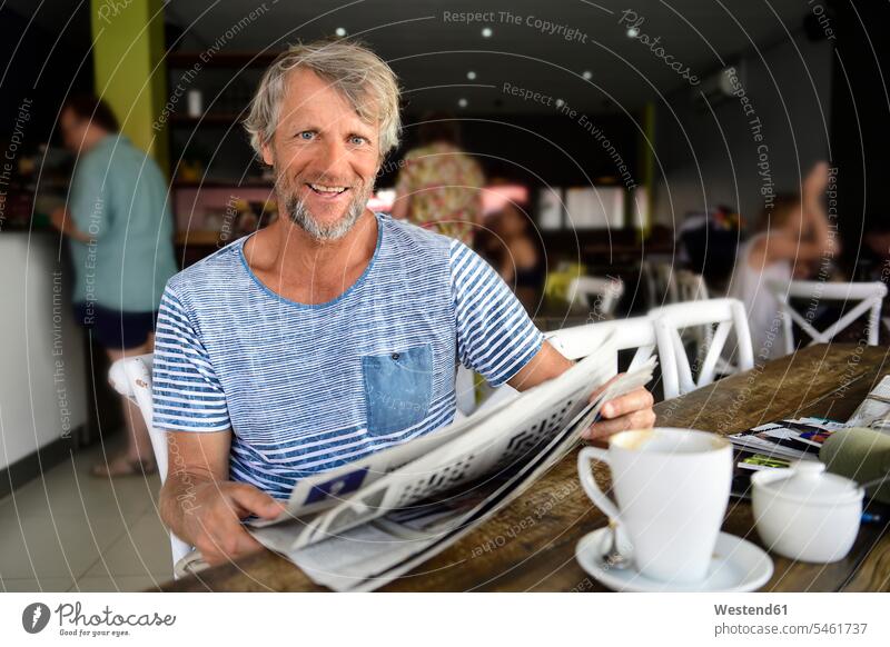 Portrait of smiling mature man sitting in a coffee shop reading newspaper portrait portraits newspapers cafe smile Seated men males Adults grown-ups grownups