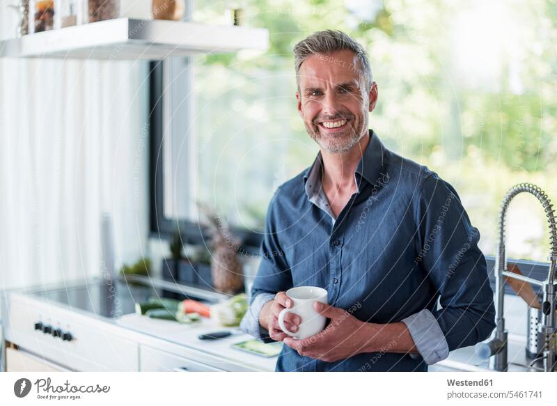 Portait of smiling mature man at home in kitchen with cup of coffee portrait portraits smile men males Coffee Cup Coffee Cups Adults grown-ups grownups adult