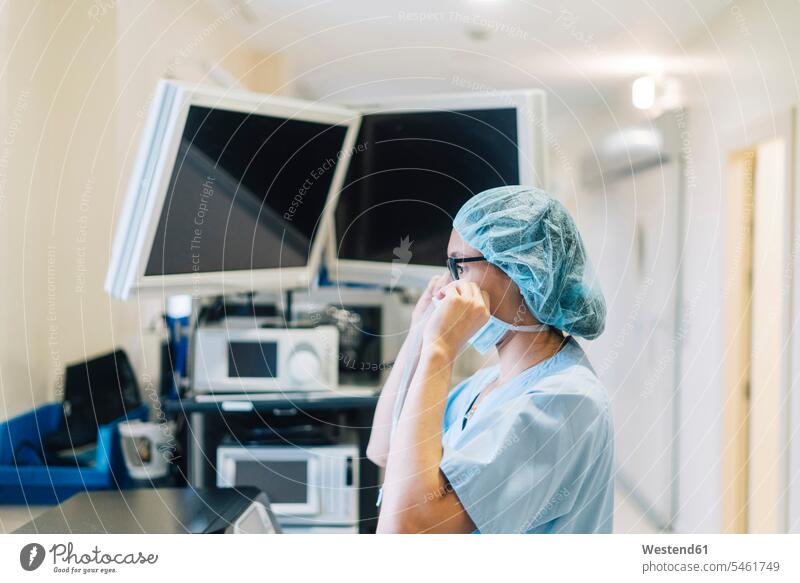 Female doctor tying surgical mask, preparing for surgery caucasian caucasian ethnicity caucasian appearance european Head and shoulders upper body