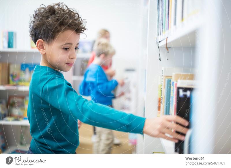 Schoolboy taking book from shelf in school library books Shelve rack racks shelves take schools Schoolboys Knowledge Intelligence intelligent learning