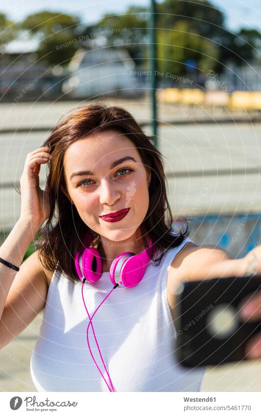 Portrait of smiling young woman with headphones and cell phone in the city headset mobile phone mobiles mobile phones Cellphone cell phones town cities towns