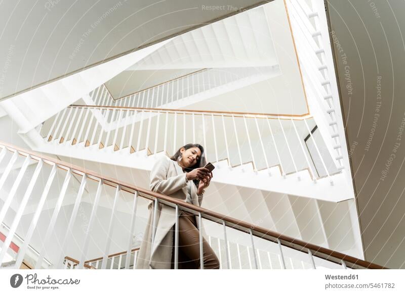 Young woman with smartphone walking down stairs in staircase telecommunication phones telephone telephones cell phone cell phones Cellphone mobile mobile phones