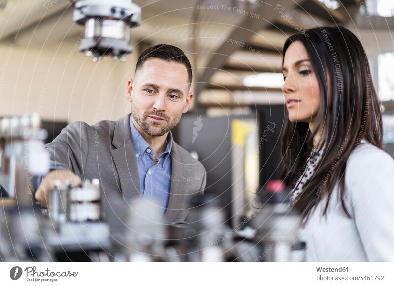 Businessman and businesswoman examining workpieces in factory checking examine factories talking speaking modern contemporary Business man Businessmen