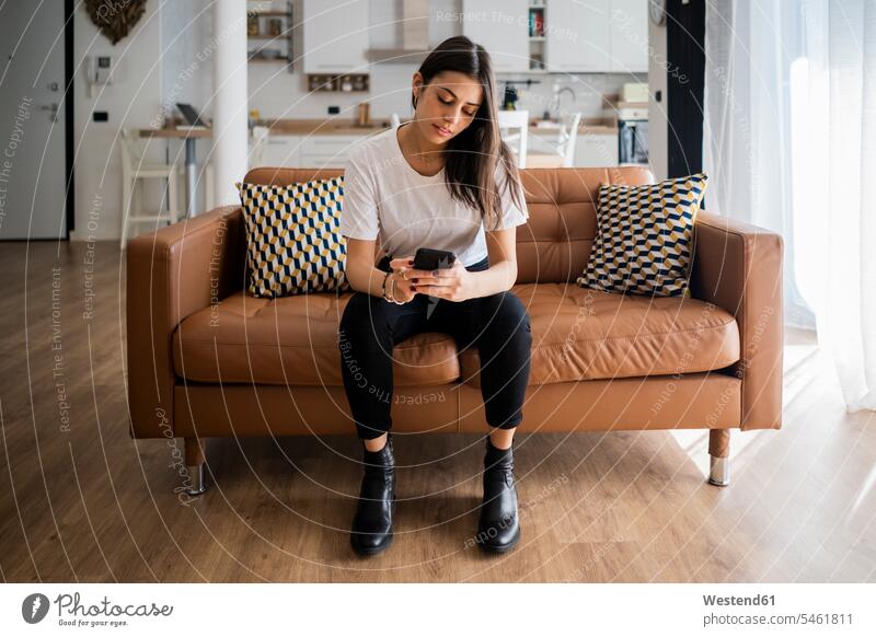 Young woman on couch at home using cell phone human human being human beings humans person persons adult grown-up grown-ups grownup grownups young young adult