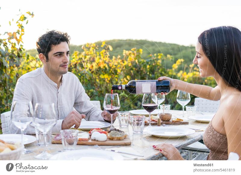 Italy, Tuscany, Siena, young couple having dinner in a vineyard with red wine Red Wine Red Wines Dinner Evening Meals Dinners Supper Suppers twosomes