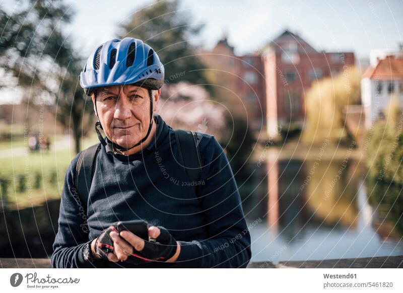 Portrait of senior man with cycling helmet using smartphone riding bicycle riding bike bike riding bicycling pedaling senior men elder man elder men
