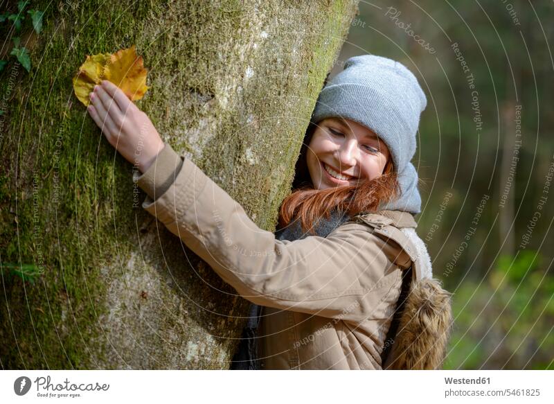 Portrait of smiling teenage girl hugging tree trunk in autumnal forest Tree Trees Teenage Girls female teenagers portrait portraits embracing embrace