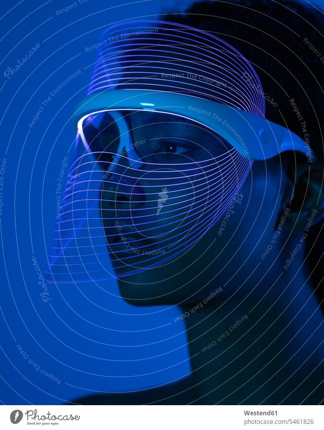 Close-up of young woman wearing blue led mask against wall at home color image colour image Millennials Millennial Generation young adults Adults grownup