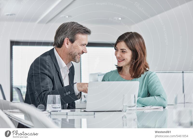 Businessman and businesswoman having a meeting in office with laptop offices office room office rooms Business Meeting business conference businesswomen