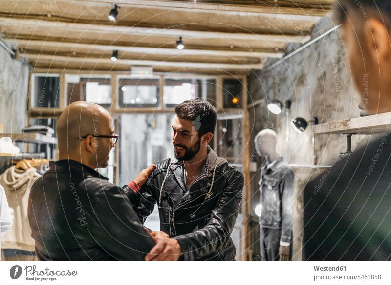 Two smiling men meeting in modern menswear shop man males smile men's fashion contemporary customer clientele clients customers Adults grown-ups grownups adult