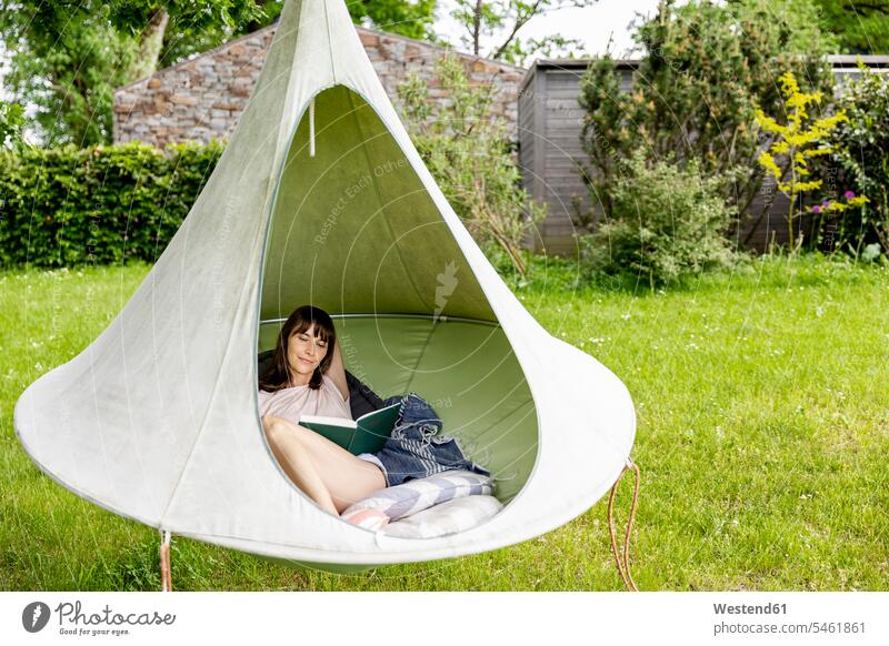 Relaxed woman reading book in a hanging tent human human being human beings humans person persons caucasian appearance caucasian ethnicity european 1