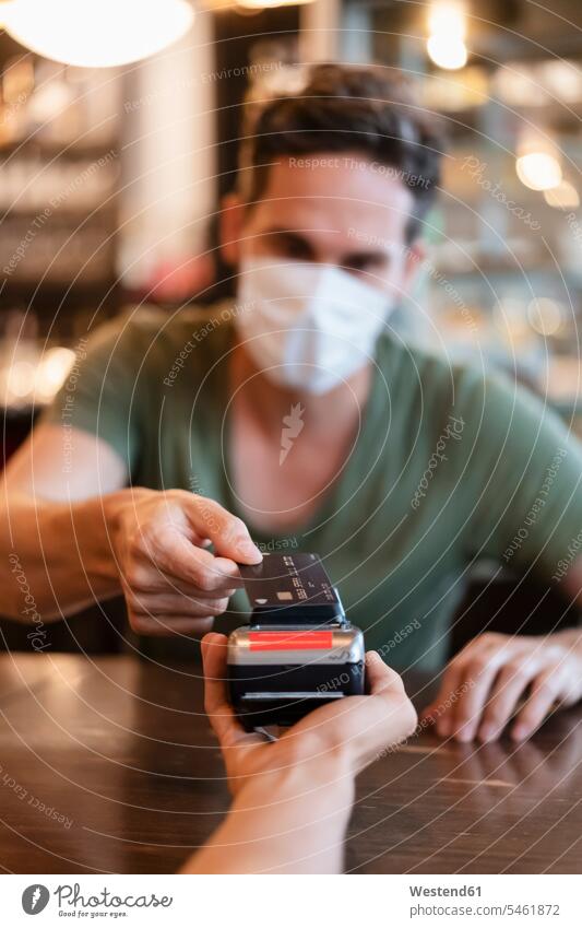 Man with protective mask paying with credit card in restaurant human human being human beings humans person persons caucasian appearance caucasian ethnicity