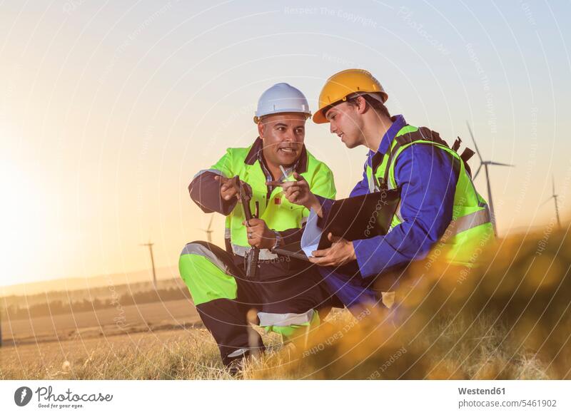 Two technicians discussing on a wind farm at sunset wind turbine wind turbines discussion wind energy wind power renewable energy alternative energy ecology
