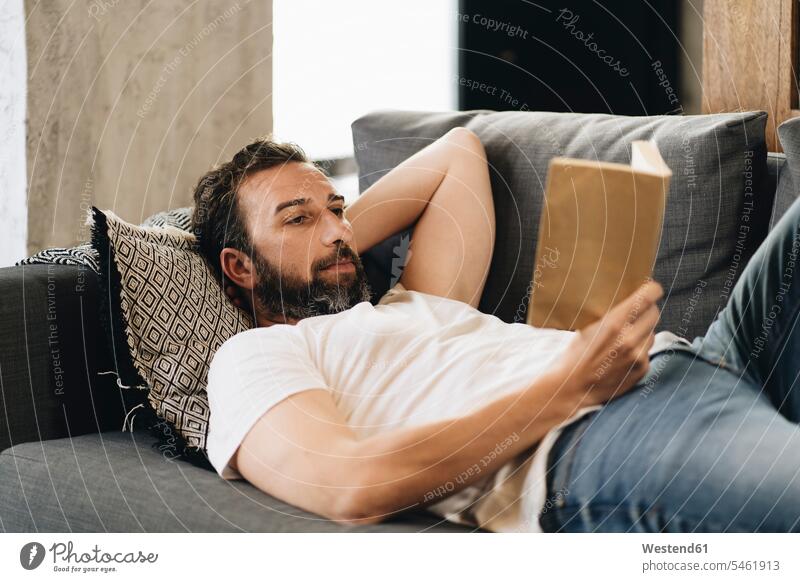 Mature man lying on couch, reading book human human being human beings humans person persons caucasian appearance caucasian ethnicity european 1 one person only