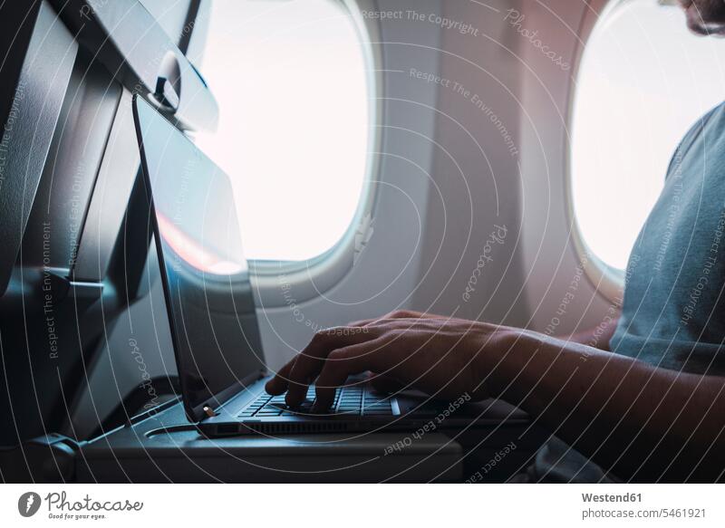 Man using laptop in airplane use sitting Seated Laptop Computers laptops notebook computer computers caucasian caucasian ethnicity caucasian appearance european