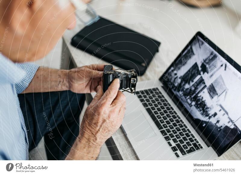 Senior man using laptop and holding his old photo camera, screen with old photo hobby hobbies senior men senior man elder man elder men senior citizen wireless