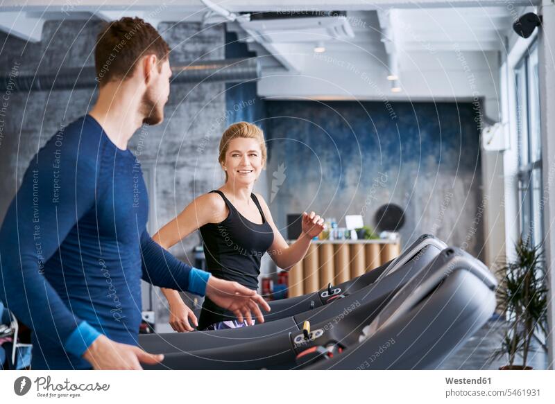 Man and woman talking during treadmill exercise at gym gyms Health Club running females women Treadmills running machine fitness sport sports Adults grown-ups