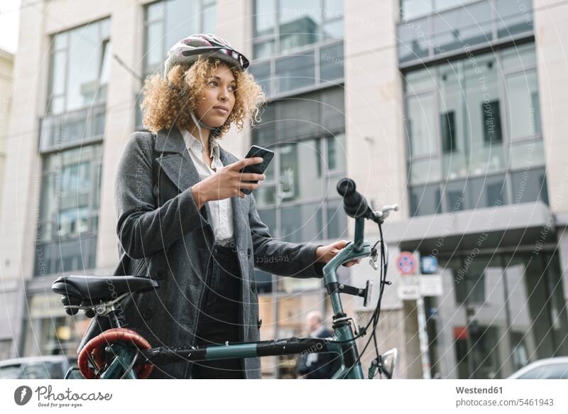 Woman with bicycle and smartphone in the city, Berlin, Germany business life business world business person businesspeople business woman business women
