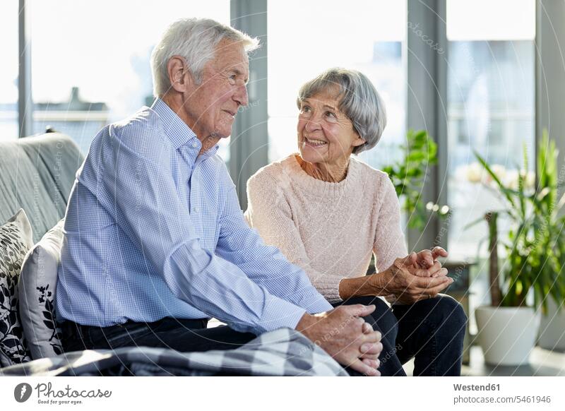 Senior couple sitting on couch talking together settee sofa sofas couches settees twosomes partnership couples senior couple elder couples senior couples