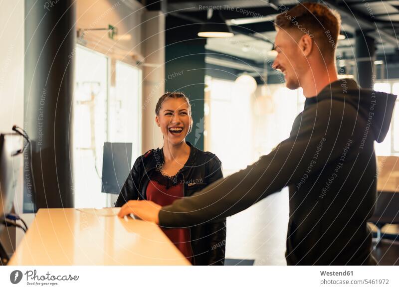 Laughing young woman talking to coach at front desk of a gym human human being human beings humans person persons caucasian appearance caucasian ethnicity
