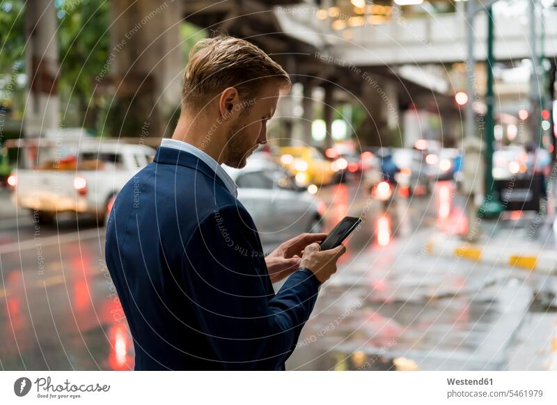 Young businessman using smartphone in Bangkok during a rainy day human human being human beings humans person persons caucasian appearance caucasian ethnicity