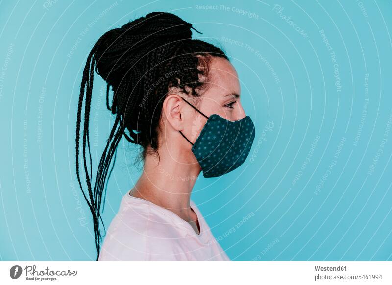 Woman wearing protective face mask with hair bun against turquoise background color image colour image Spain casual clothing casual wear leisure wear