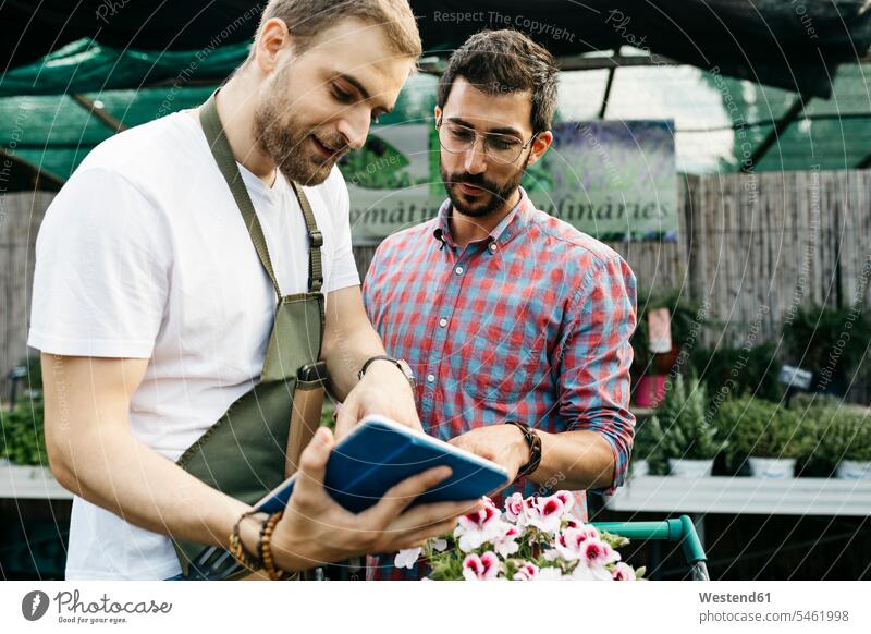 Worker with tablet in a garden center advising customer human human being human beings humans person persons caucasian appearance caucasian ethnicity european