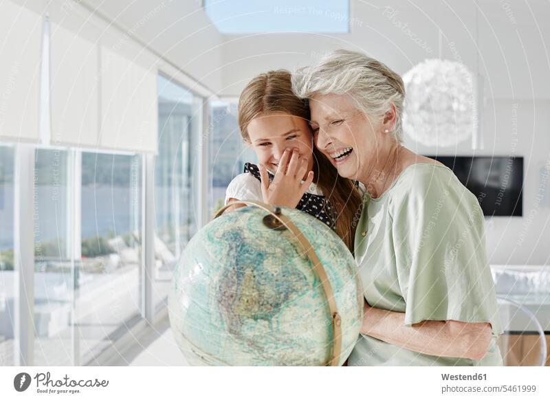 Laughing grandmother and granddaughter with globe in a villa generation windows globes delight enjoyment Pleasant pleasure Cheerfulness exhilaration gaiety gay
