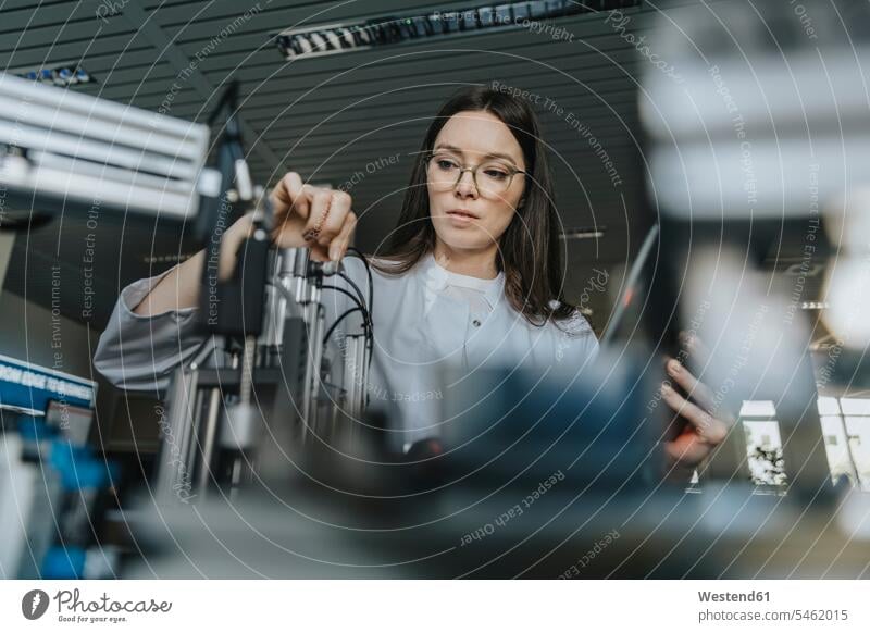 Young female scientist examining machinery in laboratory color image colour image indoors indoor shot indoor shots interior interior view Interiors science