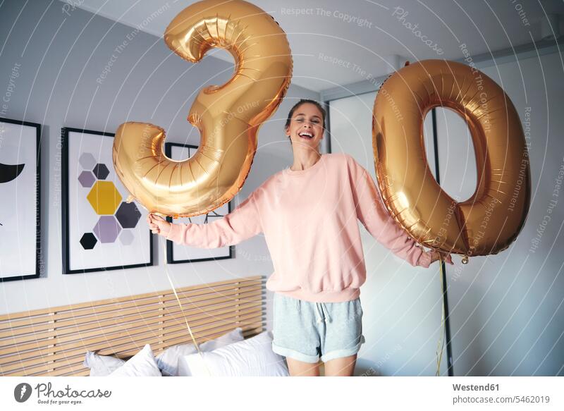 Portrait of cheerful woman with golden balloons, celebrating her birthday alone solitary solo smiling smile bed beds females women happiness happy Birthday
